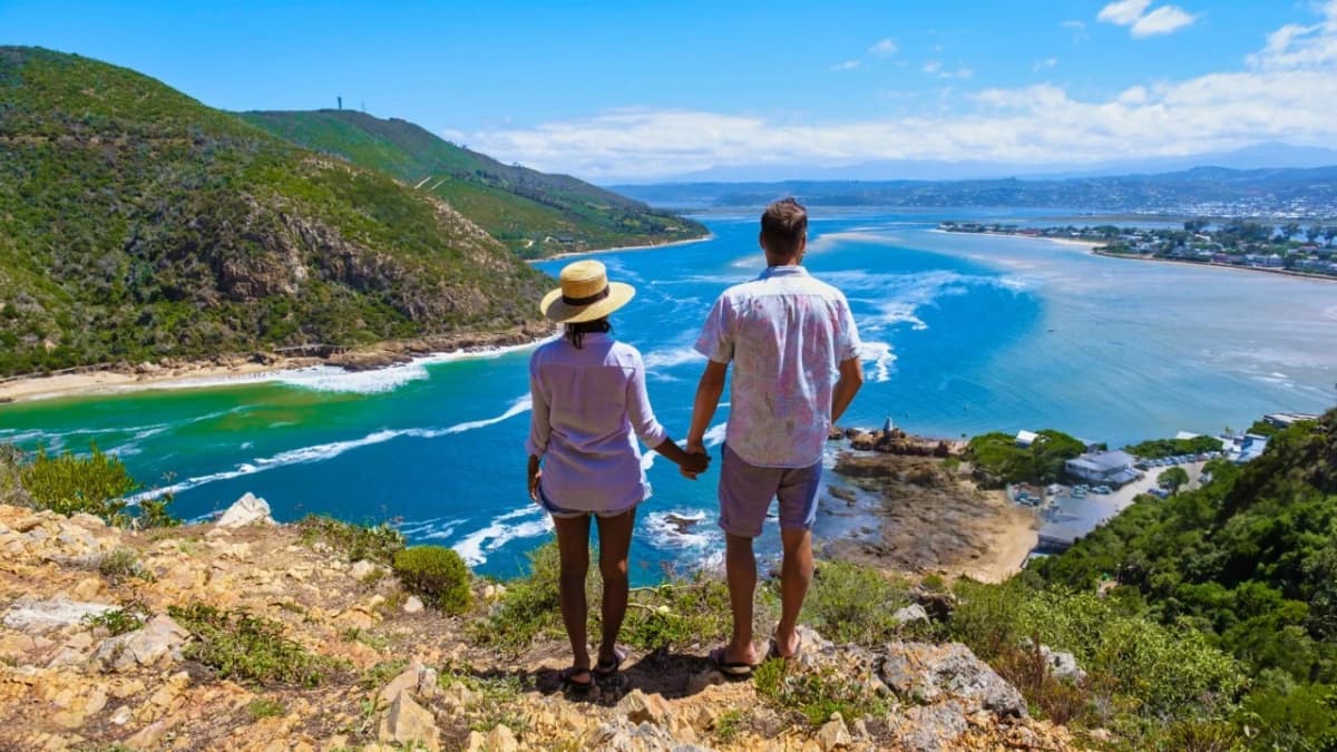 Couple standing on a hill overlooking the ocean along South Africa’s coastline during a 5-Day Garden Route Adventure, capturing scenic cliffs, blue water, and coastal landscape.